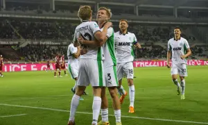 Piłkarze Sassuolo świętują bramkę podczas rozgrywek. Dwóch zawodników przytula się na boisku, podczas gdy inni cieszą się z sukcesu.