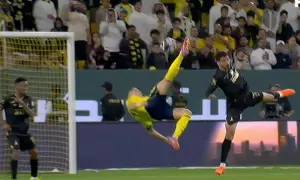 Piłkarz w żółtym stroju wykonuje spektakularny **gol z przewrotki**, akrobacja zapiera dech w piersiach.