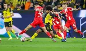 Piłkarze w czerwonych strojach walczą o piłkę na boisku podczas meczu **Bundesliga: rozgrywki**.