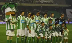 Drużyna Real Betis – zawodnicy w zielono-białych strojach pozują do zdjęcia z maskotką.