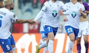 Piłkarze Lecha Poznań w białych strojach, jeden z numerem 5, gratulują sobie po meczu z Fiorentiną.