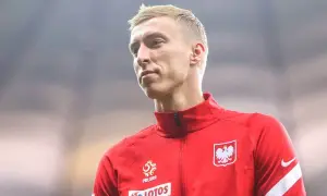 Adam Buksa w czerwonej bluzie reprezentacji Polski, z orłem na piersi.
