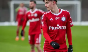 Młody piłkarz Igor Strzałek w czerwonej koszulce z numerem 86, na boisku.