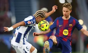 Piłkarze walczą o piłkę. Jeden z nich, Frenkie de Jong, w niebiesko-czerwonym stroju, wydaje się być w trakcie akcji, która mogła doprowadzić do jego kontuzji.