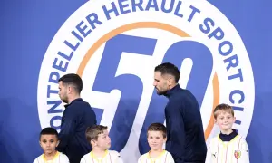 Piłkarze Montpellier HSC, klubu z ligi francuskiej, pozują z młodymi kibicami przed banerem z okazji 50-lecia klubu.