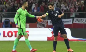 Piłkarze Polski i San Marino po meczu. Bramkarz w zielonej koszulce podaje rękawice zawodnikowi w granatowym stroju.