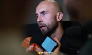 Adrian Mierzejewski udziela wywiadu dziennikarzom, odpowiadając na pytania przed mikrofonami.