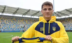 Filip Kocaba, młody piłkarz, prezentuje nowy strój na tle stadionu.