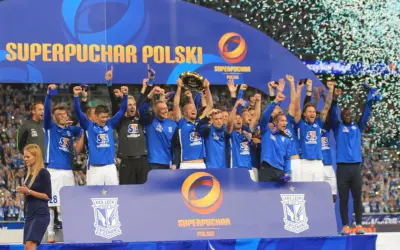 Piłkarze świętują zdobycie Superpucharu Polski, unosząc trofeum i ciesząc się deszczem konfetti.