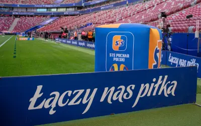 Stadion przed meczem STS Puchar Polski. Na zielonej murawie i trybunach widać logotypy i hasło "Łączy nas piłka".