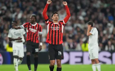 Piłkarz AC Milan z podniesionymi rękami świętuje zwycięstwo nad Realem Madryt.
