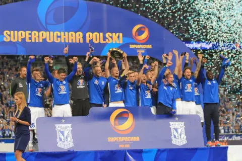Piłkarze świętują zdobycie Superpucharu Polski, unosząc trofeum i ciesząc się deszczem konfetti.