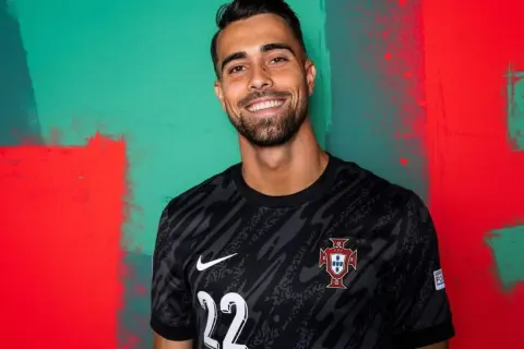 Uśmiechnięty Diogo Costa w czarnej koszulce reprezentacji Portugalii z numerem 22.