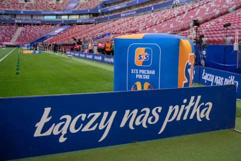 Stadion przed meczem STS Puchar Polski. Na zielonej murawie i trybunach widać logotypy i hasło "Łączy nas piłka".