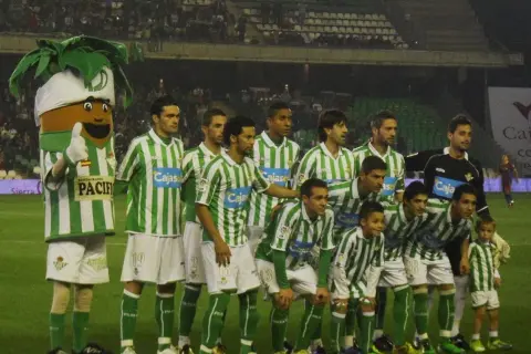 Drużyna Real Betis – zawodnicy w zielono-białych strojach pozują do zdjęcia z maskotką.