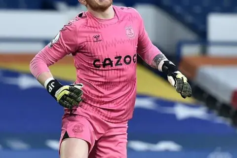 Jordan Pickford, bramkarz Anglii, w różowym stroju Evertonu, gotowy do obrony.