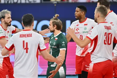 Siatkarze w białych strojach z czerwonymi elementami i jeden w zielonym, świętują zwycięstwo. To ważne mecze dla reprezentacji Polski, która walczy o kolejne punkty.