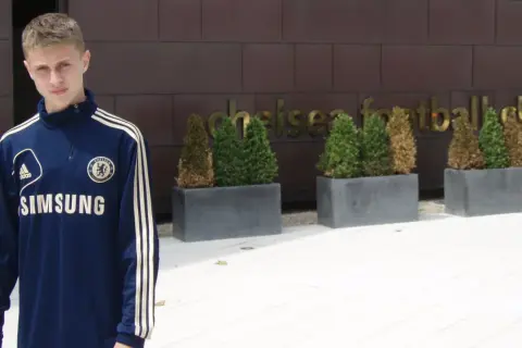 Młody Hubert Adamczyk w dresie Chelsea przed klubem.