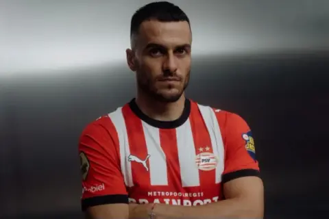 Piłkarz Filip Kostić w czerwono-białej koszulce PSV z dumą prezentuje swój nowy klub.