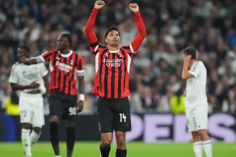 Piłkarz AC Milan z podniesionymi rękami świętuje zwycięstwo nad Realem Madryt.