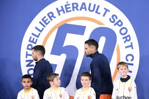 Piłkarze Montpellier HSC, klubu z ligi francuskiej, pozują z młodymi kibicami przed banerem z okazji 50-lecia klubu.