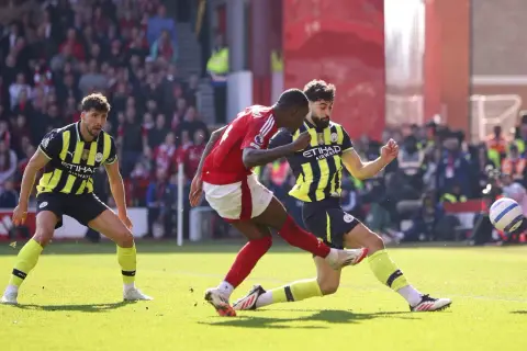 Piłkarze Nottingham Forest i Man City walczą o piłkę na boisku.