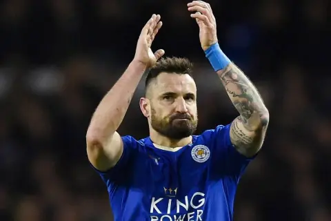 Piłkarz Leicester City, jeden z zawodników Premier League, z tatuażami na ramieniu, klaszcze po meczu.