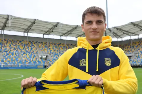 Filip Kocaba, młody piłkarz, prezentuje nowy strój na tle stadionu.