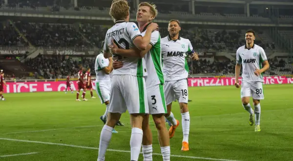 Piłkarze Sassuolo świętują bramkę podczas rozgrywek. Dwóch zawodników przytula się na boisku, podczas gdy inni cieszą się z sukcesu.