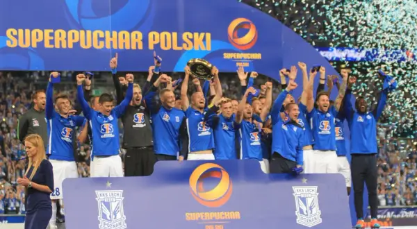 Piłkarze świętują zdobycie Superpucharu Polski, unosząc trofeum i ciesząc się deszczem konfetti.