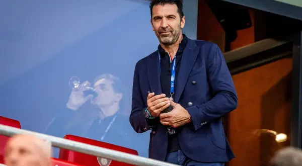Gianluigi Buffon, jeden z najlepszych włoskich bramkarzy, w eleganckim garniturze obserwuje mecz.