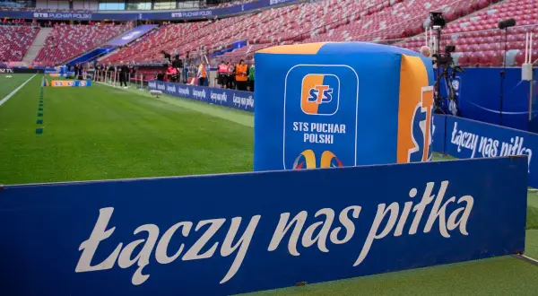 Stadion przed meczem STS Puchar Polski. Na zielonej murawie i trybunach widać logotypy i hasło "Łączy nas piłka".