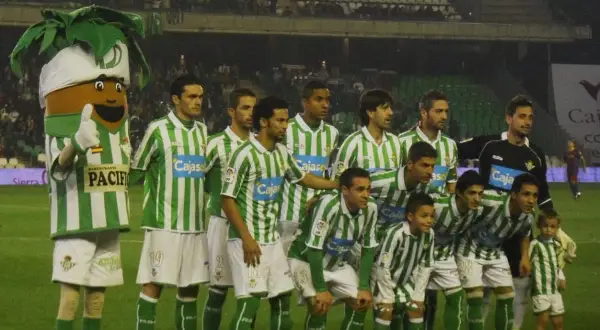 Drużyna Real Betis – zawodnicy w zielono-białych strojach pozują do zdjęcia z maskotką.