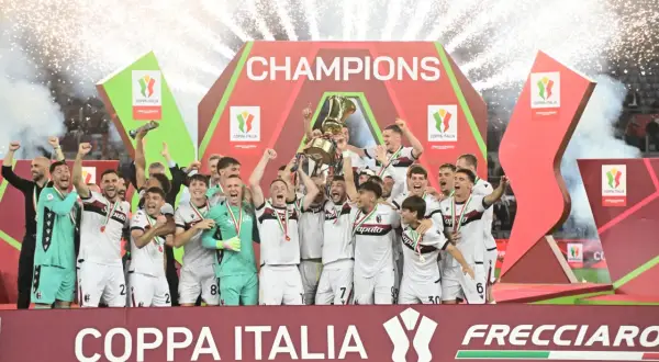 Bologna FC świętuje zwycięstwo w rozgrywkach Coppa Italia, wznosząc puchar na tle fajerwerków i napisu "CHAMPIONS".