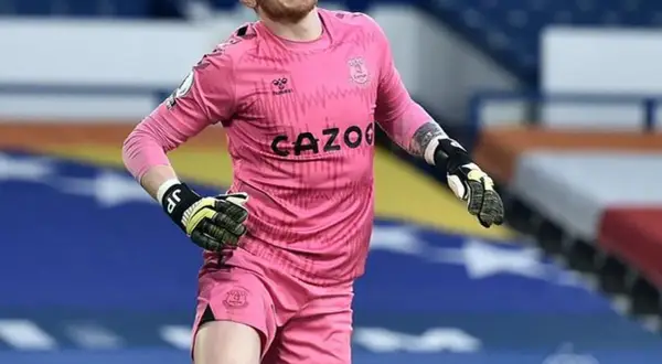 Jordan Pickford, bramkarz Anglii, w różowym stroju Evertonu, gotowy do obrony.