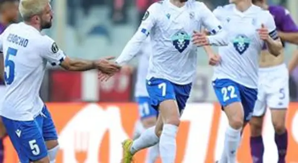 Piłkarze Lecha Poznań w białych strojach, jeden z numerem 5, gratulują sobie po meczu z Fiorentiną.