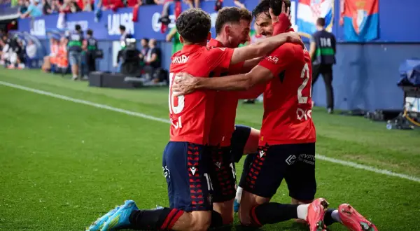 Piłkarze Osasuna FC świętują zwycięstwo, przytulając się na boisku.