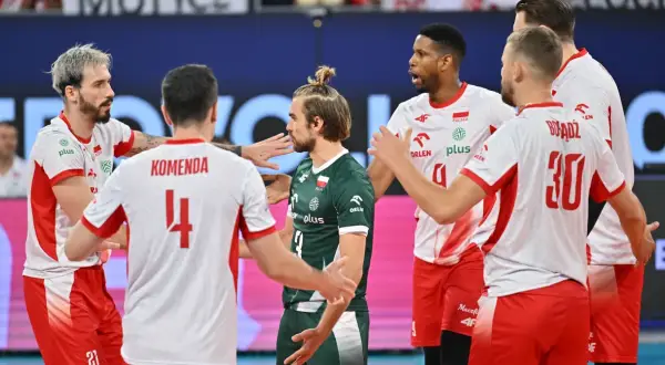 Siatkarze w białych strojach z czerwonymi elementami i jeden w zielonym, świętują zwycięstwo. To ważne mecze dla reprezentacji Polski, która walczy o kolejne punkty.