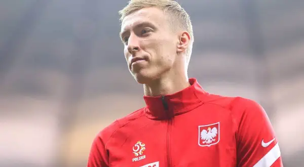 Adam Buksa w czerwonej bluzie reprezentacji Polski, z orłem na piersi.
