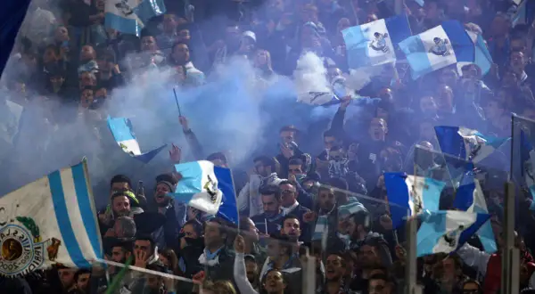 Tłum kibiców Lazio Rzym świętuje, machając flagami i odpalając race.