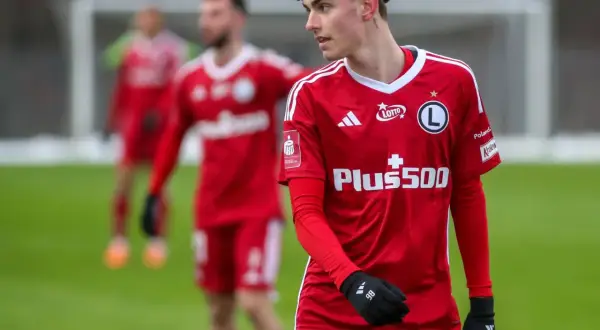 Młody piłkarz Igor Strzałek w czerwonej koszulce z numerem 86, na boisku.