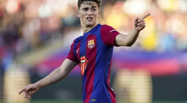 Młody gavi pilkarz FC Barcelony w akcji, z wyrazem skupienia na twarzy i uniesionym palcem wskazującym.