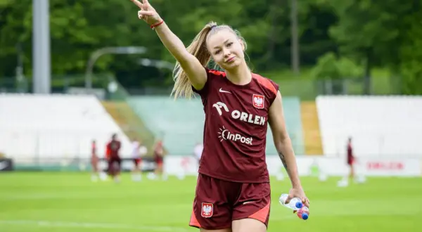 Weronika Zawistowska w dresie reprezentacji Polski, z butelką wody w dłoni, pokazuje znak pokoju.