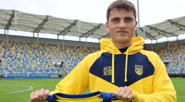 Filip Kocaba, młody piłkarz, prezentuje nowy strój na tle stadionu.