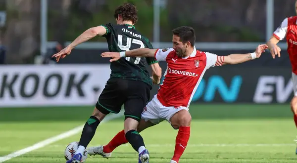 Piłkarze w akcji podczas rozgrywek SC Braga. Jeden w czerwonej koszulce, drugi w zielonej.