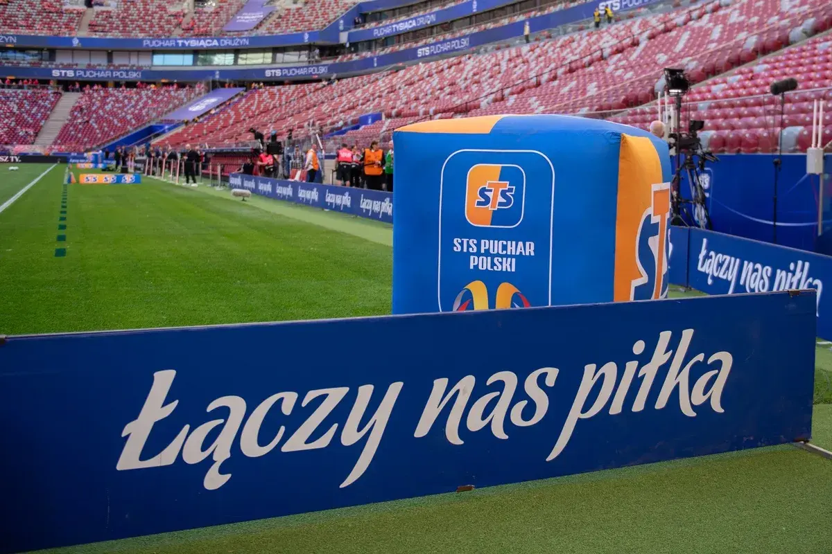 Stadion przed meczem STS Puchar Polski. Na zielonej murawie i trybunach widać logotypy i hasło "Łączy nas piłka".