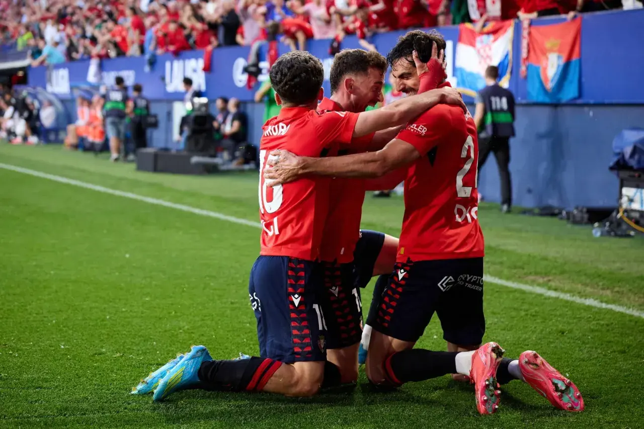 Piłkarze Osasuna FC świętują zwycięstwo, przytulając się na boisku.