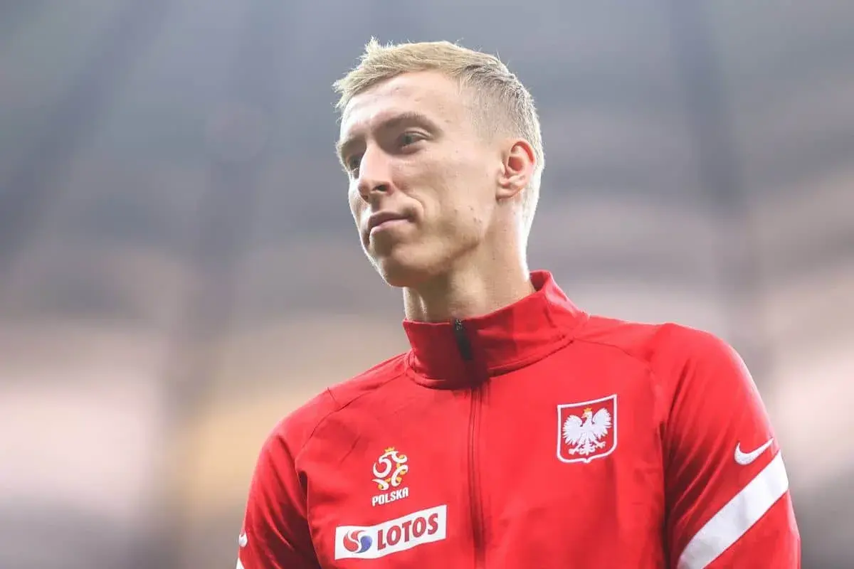 Adam Buksa w czerwonej bluzie reprezentacji Polski, z orłem na piersi.