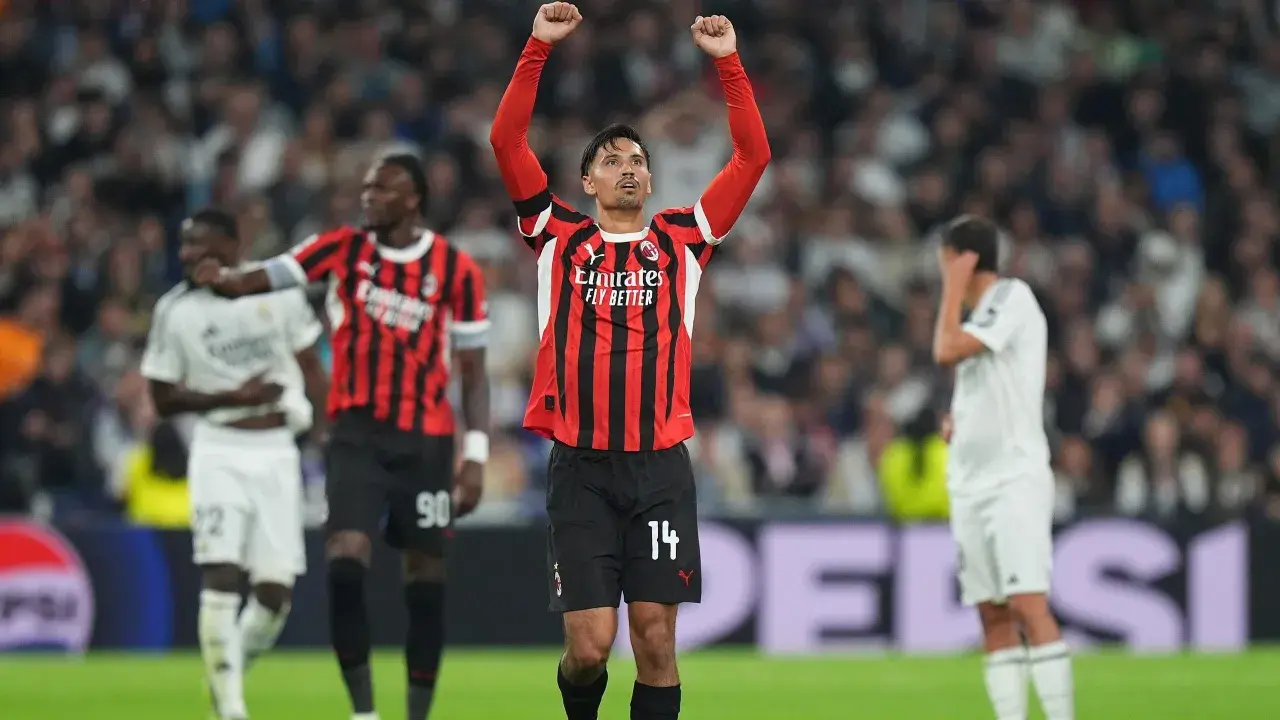 Piłkarz AC Milan z podniesionymi rękami świętuje zwycięstwo nad Realem Madryt.