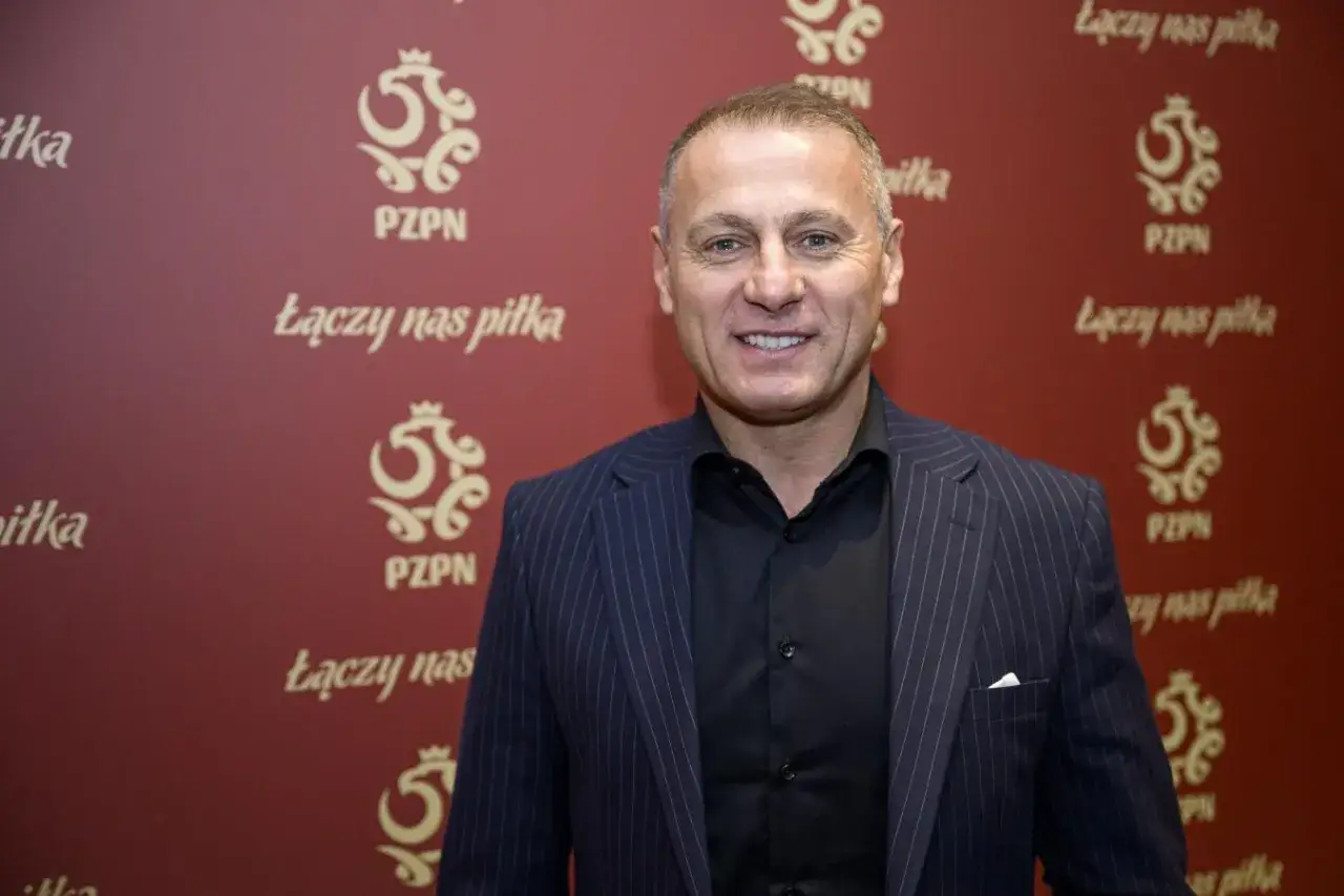 Piotr Świr Świerczewski w garniturze na tle czerwonej ścianki z logo PZPN i hasłem 